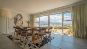 een eetkamer met een tafel en stoelen en een groot raam bij Swallows Rest - Benguela Cove in Hermanus