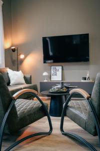 een woonkamer met twee stoelen en een tv bij Traumnest Eifel mit Sauna & Whirlpool in Monschau