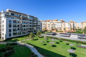 Un complejo de apartamentos con un parque con palmeras y edificios. en Los Flamencos Isla Canela I, en Isla Canela