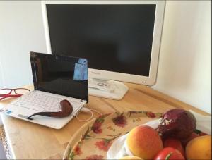 a laptop computer sitting on a desk with a plate of fruit at La Roseraie in Battipaglia