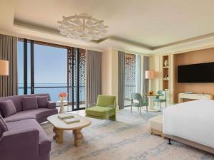 a living room with a bed and a couch and a tv at Raffles Jeddah in Jeddah