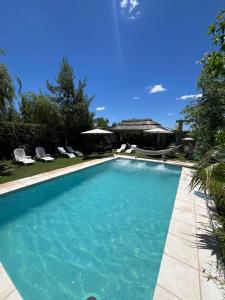 a swimming pool with blue water and chairs in a yard at Departamentos Merceditas in San Rafael
