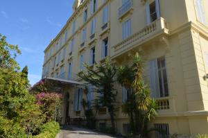 a large yellow building with trees in front of it at Hôtel Windsor in Cannes