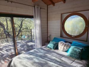 a bedroom with a bed and a large window at GITES O FIL DE L'EAU piscine spa accès rivière in Omessa