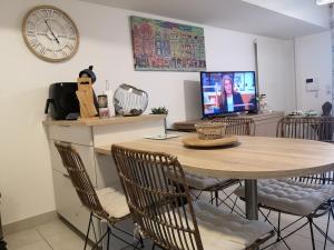 a dining room with a table and a clock on the wall at appartement 2 pieces avec parking ds résidence in Palavas-les-Flots