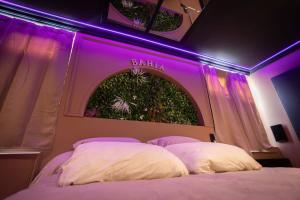 a bedroom with a bed with a purple lighting at BAHIA -Suite romantique & SPA Privé in La Roche-sur-Yon