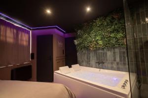 a bathroom with a tub with a plant on the wall at BAHIA -Suite romantique & SPA Privé in La Roche-sur-Yon