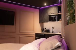 a kitchen with purple lighting and a bed in a room at BAHIA -Suite romantique & SPA Privé in La Roche-sur-Yon