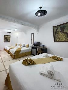 a room with three beds and a television in it at Hôtel Calipau Riad Maison d'Hôtes in Dakhla +65 photos