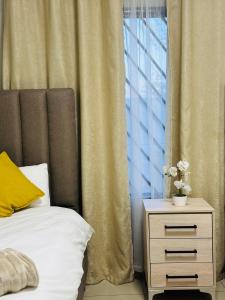 una cama con mesita de noche junto a una ventana en Graceful Getaway Home, en Rundu