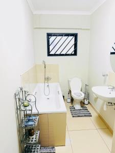 Un baño con bañera, inodoro y lavabo. en Graceful Getaway Home, en Rundu