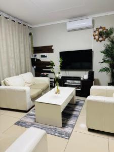Una sala de estar con muebles blancos y un televisor de pantalla plana. en Graceful Getaway Home, en Rundu