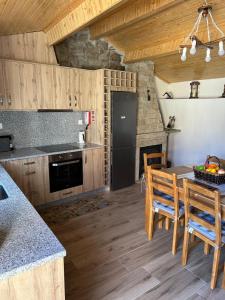 a kitchen with wooden cabinets and a table with chairs at Cantinho da Aldeia in Castedo