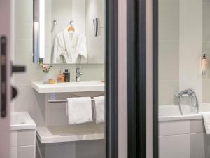 a white bathroom with a sink and a mirror at Mercure Paris Porte De Versailles Expo in Paris