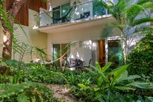 a garden in front of a house with a balcony at Papaya 15 Apartments in Playa del Carmen