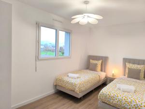 a bedroom with two beds and a window at Le Zest d'or - Douceur & Lumière à 5min en voiture de la Plage in Biville-sur-Mer