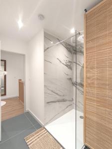 a shower in a bathroom with a glass wall at Le Zest d'or - Douceur & Lumière à 5min en voiture de la Plage in Biville-sur-Mer