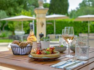 Novotel Aix-en-Provence Pont de L'Arc في آكس أون بروفانس: طاولة مع كوب من النبيذ وصحن من الطعام