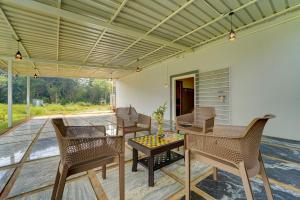 a patio with chairs and a table on a deck at Hotel O ESTORIA HOTEL & RESORT in Kadakola