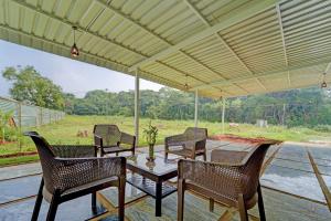 a patio with a table and chairs and a view of a field at Hotel O ESTORIA HOTEL & RESORT in Kadakola