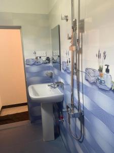 a blue tiled bathroom with a sink and a shower at Sedasi Holiday Home in Tangalle
