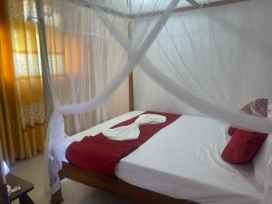 a bedroom with a canopy bed with red and white sheets at Sedasi Holiday Home in Tangalle