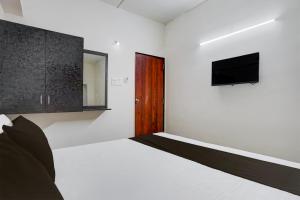 ein Schlafzimmer mit Bett und Flachbildfernseher in der Unterkunft Hotel O Sai Shlok Inn Lodging in Nashik