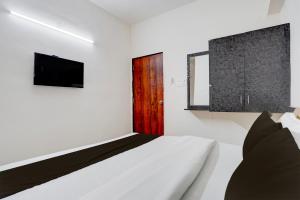 ein weißes Schlafzimmer mit einem Bett und einem Fernseher in der Unterkunft Hotel O Sai Shlok Inn Lodging in Nashik