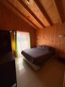 a bedroom with a bed in a wooden room at Cabañas Ebenezer in Pichidangui