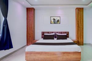 Hotel O Happy Homes Resort في Kāhārpāra: غرفة نوم مع سرير مع اللوح الأمامي الخشبي +26 صورة