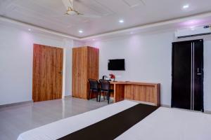 Hotel O Happy Homes Resort في Kāhārpāra: غرفة بسرير وطاولة مع كراسي