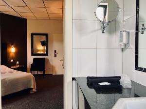 a bathroom with a bed and a sink and a mirror at Hotel Pommerloch in Pommerloch