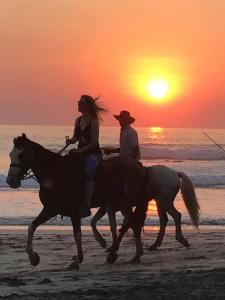 two people riding horses on the beach at sunset at Casitas Escondidas in Playa Pelada