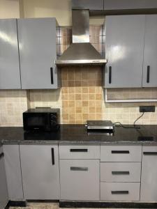 Una cocina con gabinetes blancos y una encimera negra. en The Luxe, en Jāmb