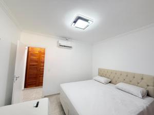 a white bedroom with a bed and a window at Flat estudio 110 Amarilis Riviera de São Lourenço, 03 piscina climatizada, serviço de hotelaria, limpesa e troca de toalhas diária, carregador veiculo elétrico e servico de praia finais de semana WiFi 500 in Riviera de São Lourenço +104 photos