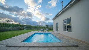 een zwembad met twee stoelen naast een huis bij Swallows Rest - Benguela Cove in Hermanus