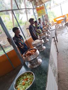 a group of men standing in a line with bowls of food at Dreamworld Waterpark Resort Virar in Virār +7 photos