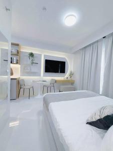 ein weißes Schlafzimmer mit einem großen Bett und einem Tisch in der Unterkunft Simple White Scape at Mesavirre Bacolod in Bacolod City