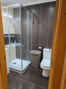 a bathroom with a toilet and a glass shower at Ático Paraíso in San Ciprián +8 photos