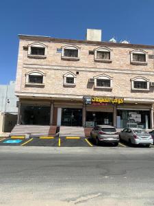 een groot bakstenen gebouw met auto's geparkeerd voor het bij الوسام ان in Taif