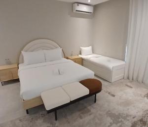 a white bedroom with two beds and a window at Al Ain Farm Escape with Private Pool , Mini Golf , and Firepit in Bin Aḩmad +6 photos