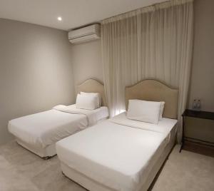 two beds in a hotel room with white sheets and pillows at Al Ain Farm Escape with Private Pool , Mini Golf , and Firepit in Bin Aḩmad