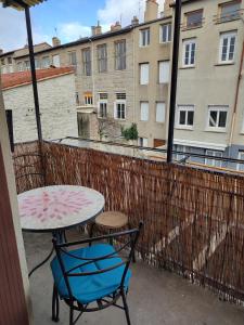 a table and a chair on a balcony with a table and a view at Appartement plein centre in Saint-Étienne