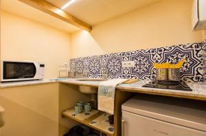 a kitchen with a sink and a microwave and a counter at Grand Suite Gioberti Elegante nel cuore di Alghero in Alghero