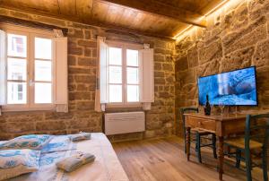 a bedroom with a bed and a desk and windows at Grand Suite Gioberti Elegante nel cuore di Alghero in Alghero