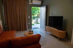 VASIADIS apartment في Síndos: غرفة معيشة مع أريكة وتلفزيون بشاشة مسطحة