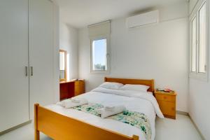 ein weißes Schlafzimmer mit 2 Betten und 2 Fenstern in der Unterkunft Elisabeth Salt Lake views 200m from Makenzy beach in Larnaka