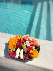 a plate of fruit on a table next to a pool at Furaha Villa Zanzibar in Kiwengwa