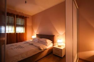 a bedroom with a bed with two lamps and a window at Apartment with garden in the center of Durres in Durrës