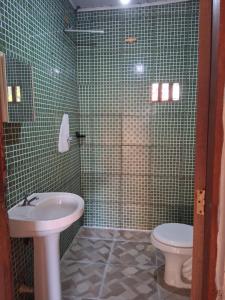 een groene betegelde badkamer met een wastafel en een toilet bij Recanto verde in Ilhabela